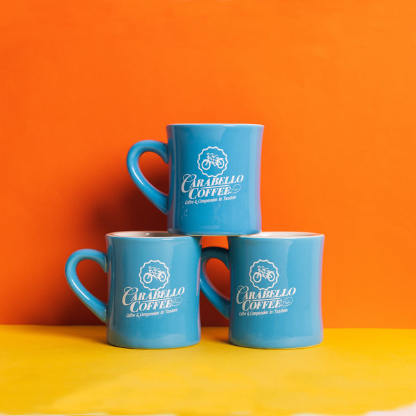 Stack of three blue diner mugs with the words Carabello Coffee on them 