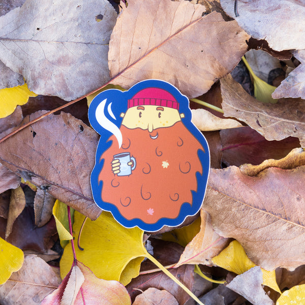 Sticker featuring cartoon man with large beard and red beanie hat.  Drinking coffee and fall leaves 