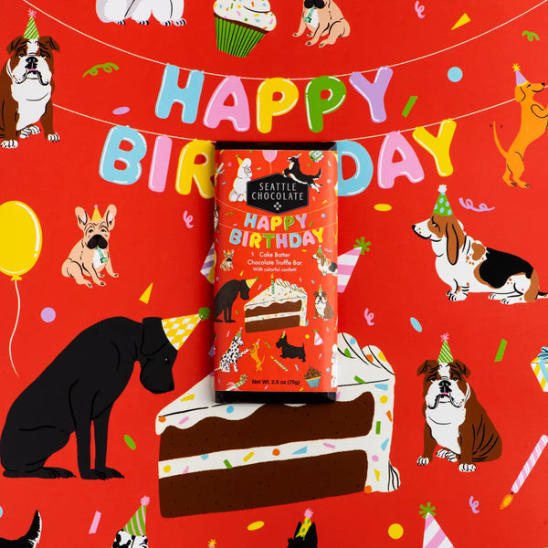 Seattle Chocolate brand chocolate bar in birthday cake flavor.  Sitting on dog themed wrapping paper.  