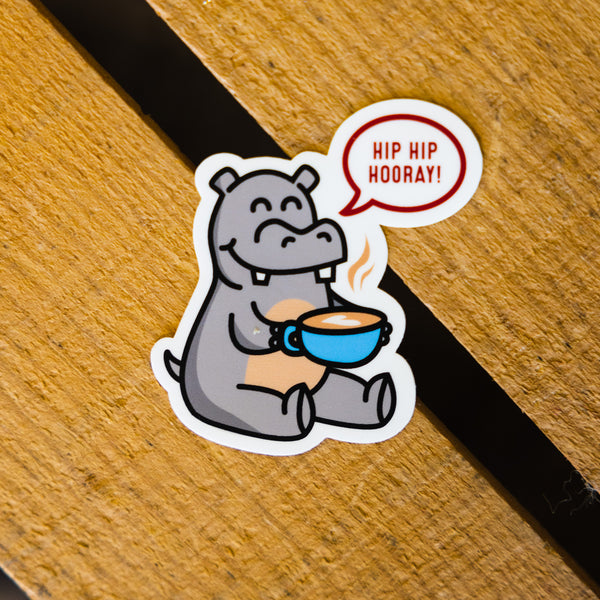 Sticker featuring a hippo having a mug of coffee saying "Hip Hip hooray" 
