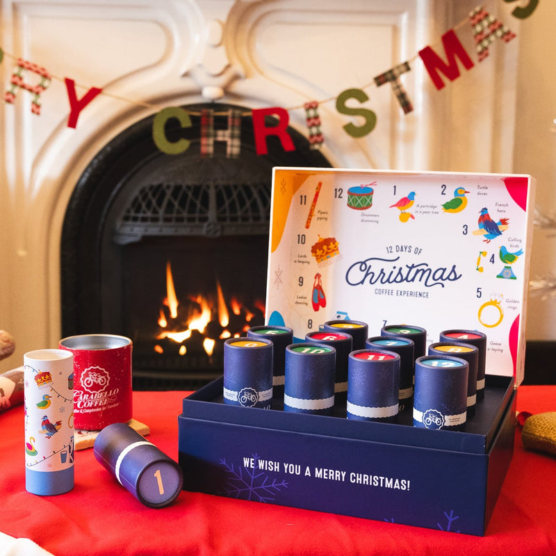 Christmas-themed products including candles, wrapping paper, and a card in front of a fireplace with Christmas decorations.