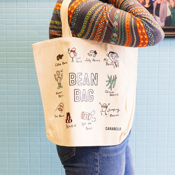 Canvas tote bag featuring puns about beans and coffee in whimsical drawings 