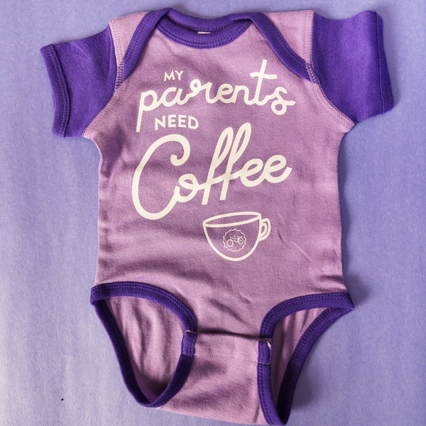 Purple baby onesie with dark purple sleeves and an image that says "My parents need coffee" 