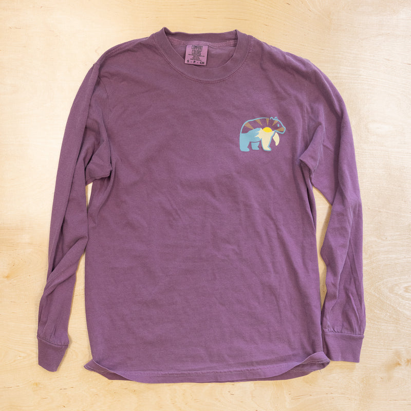 Purple long-sleeve shirt with a colorful bear design on a wooden surface
