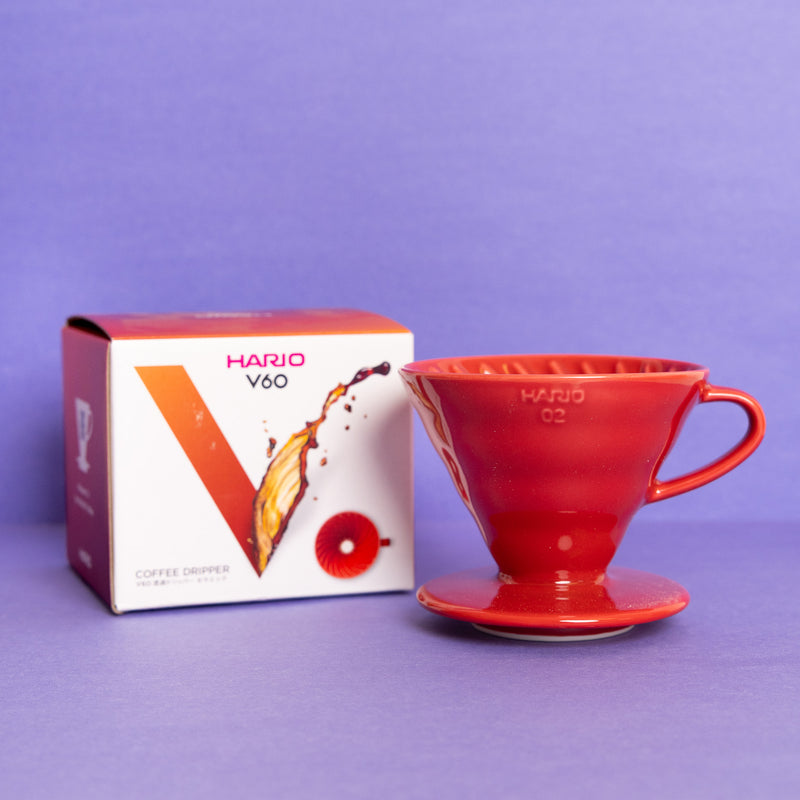 Red Hario V60 coffee dripper with packaging on a purple background