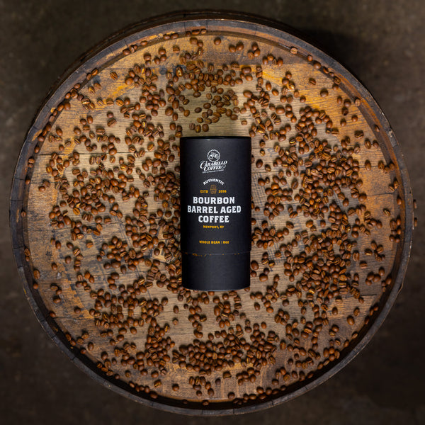 Bourbon barrel aged coffee can on a wooden barrel with coffee beans.