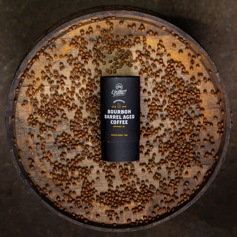 Bourbon barrel aged coffee can on a wooden barrel with coffee beans.