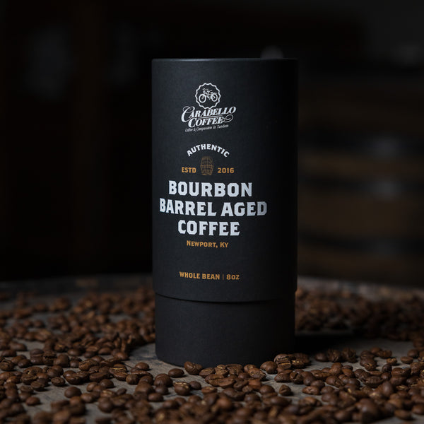 Black coffee container with 'Carabello Coffee' branding on a dark background with coffee beans.