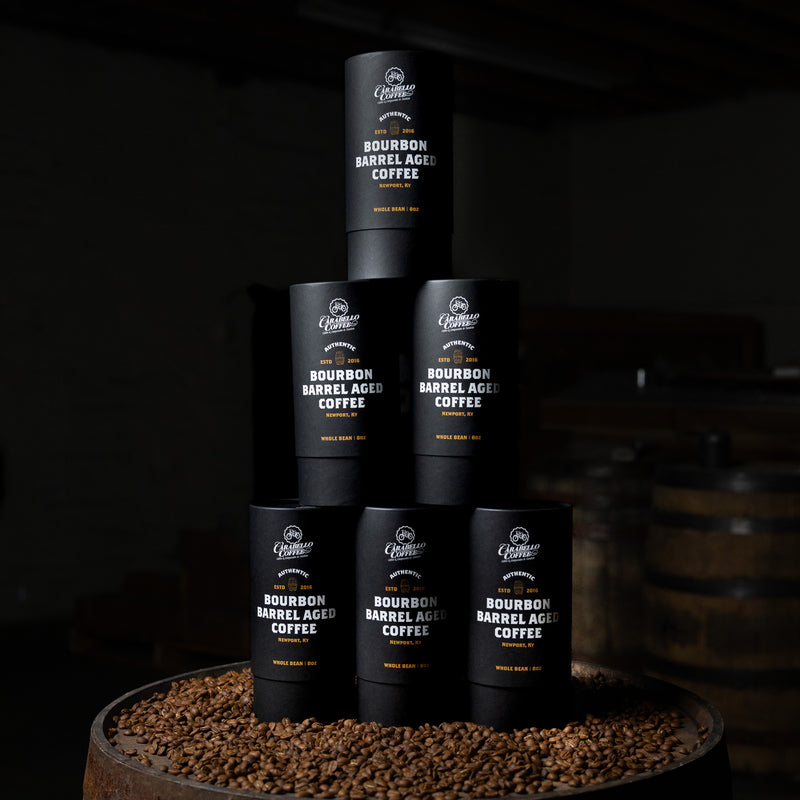 Stack of Bourbon Barrel Aged Coffee containers on a dark background