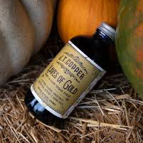 Bottle of Leaves of Gold syrup on a hay bale with pumpkins in the background.