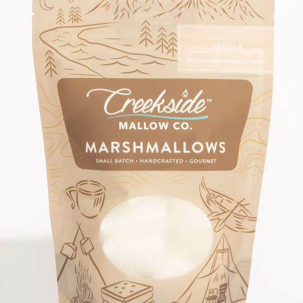 Packaging of Creekside Mallow Co. marshmallows with nature-themed illustrations on a beige background.