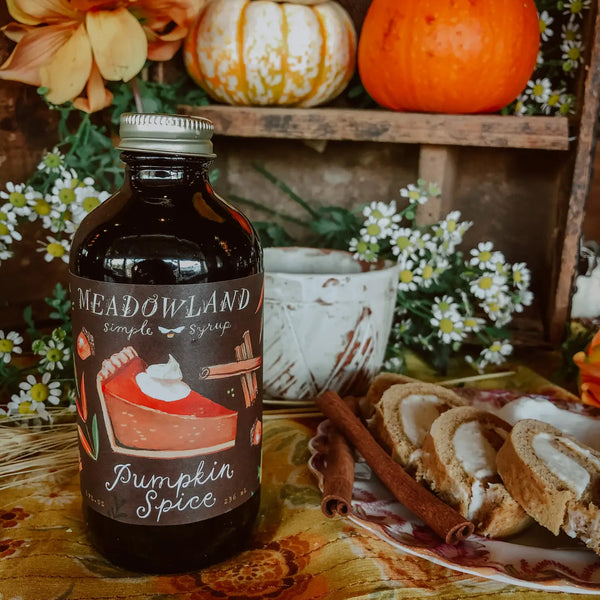 Bottle of Meadowland Pumpkin Spice syrup with pumpkins and cake in the background